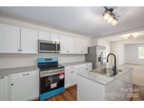 Modern kitchen featuring stainless steel appliances, white cabinets, and a center island with granite countertops at 257 3Rd Se Ave, Hickory, NC 28602