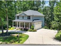 Charming two-story home with a stone facade, covered porch, and lush landscaping in a wooded setting at 463 Lake Wylie Rd, Belmont, NC 28012