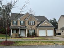 Two-story brick home featuring a two-car garage, landscaped yard, and covered front porch at 9391 Leyton Dr, Harrisburg, NC 28075