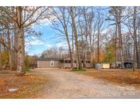 Charming tan home nestled among mature trees with a spacious front yard and plenty of privacy at 153 Cheshire Ridge Rd, Harmony, NC 28634