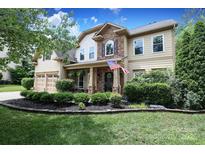 Inviting two-story home featuring a stone facade, well-manicured lawn, and a charming front garden at 1800 Robbins Meadows Dr, Waxhaw, NC 28173