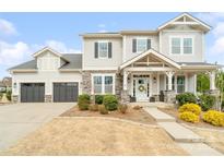 Charming two-story home featuring stone accents, inviting front porch, and well-manicured landscaping at 2150 Paddlers Cove Dr, Clover, SC 29710