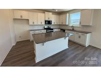 Bright kitchen featuring white cabinets, gray countertops, an island, and stainless steel appliances at 317 Maidstone Dr # 57, Monroe, NC 28110