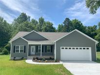 Charming single-story home with a well-manicured lawn, gray siding, and an attached white two-car garage at 325 East St, Heath Springs, SC 29058