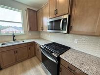 Well-lit kitchen features granite countertops, stainless steel appliances and ample wood cabinets at 346 Knotty Wood Dr # 71, Monroe, NC 28110