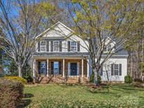 Charming two-story home with a welcoming front porch, manicured lawn, and mature trees at 111 Forest Walk Way, Mooresville, NC 28115