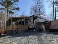 Exterior view of an RV featuring a covered porch and surrounding gravel landscape at 156 Arrowood Trl # F26, Mount Gilead, NC 27306