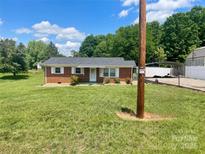 Charming brick home featuring a lush lawn, complemented by crisp white shutters and a covered front porch entrance at 1802 Young Dr, Conover, NC 28613
