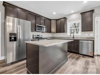 Gourmet kitchen features stainless appliances, dark wood cabinets, granite counters, and new luxury vinyl plank flooring at 1313 Gidney St, Shelby, NC 28150
