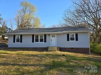 Charming single-story home with gray siding, black shutters and a well-maintained front yard at 211 W Roswell St, Troy, NC 27371