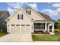 Charming home featuring a two-car garage, classic tan siding, and a welcoming front porch at 10421 Superb Ln, Charlotte, NC 28215