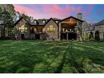 Expansive backyard featuring lush green grass and a brick house with a stone fireplace and open porch at 1614 Shimron Ln, Waxhaw, NC 28173