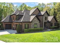 Elegant brick and stone home with a lush green lawn and mature landscaping at 1614 Shimron Ln, Waxhaw, NC 28173