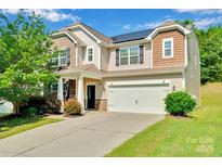 Charming two-story home featuring stone accents, solar panels, a two-car garage and a well-manicured lawn at 1923 Caprington Dr, Fort Mill, SC 29707