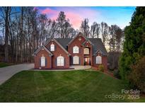 Charming brick home with a manicured lawn and mature trees, set against a picturesque sky at dusk at 2846 Snead Ne Ct, Conover, NC 28613