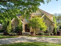 Charming stone home with a beautiful front yard and mature trees creating an inviting entrance at 5811 Old Well House Rd, Charlotte, NC 28226