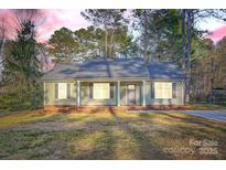 Charming single-story home with a welcoming front porch and classic gray shutters, all surrounded by lush greenery at 714 Sunset Dr, Salisbury, NC 28147