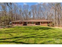 Charming ranch-style home featuring brick facade, red shutters, a well-maintained lawn, and a lush tree-lined backdrop at 220 Gregory Rd, Salisbury, NC 28147