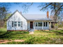 Charming one-story home featuring white siding, a metal roof, and a welcoming front porch at 260 Penninger Dr, Woodleaf, NC 27054