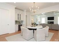 Bright dining area with modern chandelier, built-in bar and view into large living room at 3119 Knowlton Ln, Charlotte, NC 28205