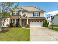 Charming two-story home featuring a well-maintained lawn, two-car garage, and classic brick and siding exterior at 320 Allspice Rd, Fort Mill, SC 29708