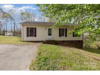 Charming single-story home featuring red shutters, siding and a gravel driveway surrounded by a lush, green lawn at 410 E Lee Ave, Bessemer City, NC 28016