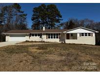 Charming one-story home with white painted brick, brown roof, and attached garage at 614 Hazelwood Dr, Albemarle, NC 28001