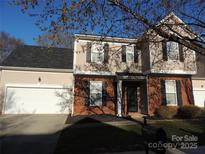 Charming two-story home featuring a brick facade, neutral siding, and an attached two-car garage at 7814 Rolling Meadows Ln, Huntersville, NC 28078