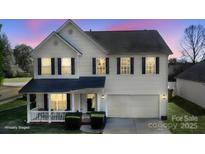 Charming two-story home with black shutters, a covered porch, a two-car garage, and manicured landscaping at 1016 Council Fire Cir, Indian Trail, NC 28079