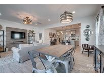 Open-concept living room and dining area with a decorative wall and modern light fixtures at 11120 Pagebrook Ln, Charlotte, NC 28214