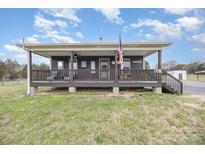 Charming cabin with a welcoming front porch and American flag, perfect for relaxing outdoors at 1640 Bear Poplar Rd, Cleveland, NC 27013