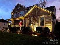 Charming home with a welcoming front porch, American flag, and professional landscape lighting at 7240 Baybrooke Ln, Harrisburg, NC 28075