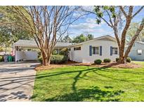 Charming brick home featuring a well-manicured lawn, mature trees, and covered carport at 821 Fairbanks Rd, Charlotte, NC 28210