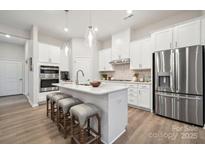 Bright kitchen with stainless steel appliances, white cabinets, and center island with bar stool seating at 8642 Miles Gap Rd, Indian Land, SC 29707