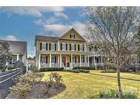 Beautiful two-story yellow home with a large front porch, black shutters, a red front door, and a well-manicured lawn at 9703 Cotton Stand Rd, Charlotte, NC 28277