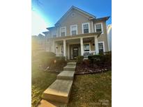 Charming two-story home featuring a welcoming front porch with white columns and landscaped front yard at 13127 Centennial Commons Pkwy, Huntersville, NC 28078