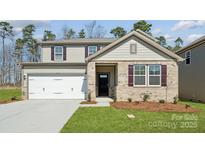 Charming two-story home featuring a brick facade, two car garage, and manicured lawn at 2581 Blue Sky Meadows Dr, Monroe, NC 28110