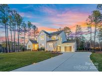 Stunning two-story home with a three-car garage, lush green lawn, and a beautifully colored sky at dusk at 6398 Chimney Bluff Rd, Lancaster, SC 29720