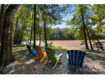 Scenic river view with colorful Adirondack chairs beneath mature trees creating a peaceful setting at 6398 Chimney Bluff Rd, Lancaster, SC 29720