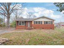 Charming single-story brick home with black shutters, a classic gable roof, and a well-manicured lawn under a blue sky at 7207 Idlewild Rd, Charlotte, NC 28212