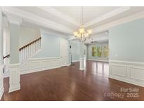 Open-concept living area with hardwood floors and an elegant staircase with classic white railings at 11037 Thornbeck Ln, Midland, NC 28107