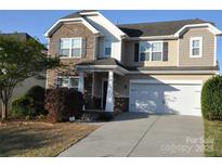 Two-story home showcasing stone and beige siding, attached two-car garage, and a well-manicured front lawn at 11621 Red Knoll Ln, Pineville, NC 28134