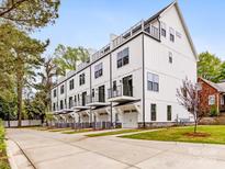 Modern white townhomes featuring balconies, garage doors, and well-maintained landscaping, perfect for contemporary living at 1413 Kenilworth Ave, Charlotte, NC 28203