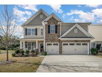 Inviting two-story home featuring a stone facade and a spacious three-car garage and manicured lawn at 276 Annatto Way, Tega Cay, SC 29708