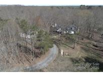 An aerial shot of a sprawling property featuring a white home with mature trees and a gravel driveway at 7218 Alexander Farm Rd, Monroe, NC 28110