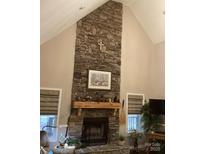 Living area with a floor-to-ceiling stone fireplace and a decorative wooden mantle at 7218 Alexander Farm Rd, Monroe, NC 28110
