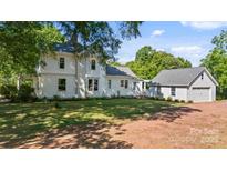 Charming two-story white farmhouse with a lush green lawn and separate garage, exuding timeless appeal at 127 Charlotte St, Mooresville, NC 28115