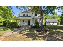 Charming two-story white home with a covered front porch and a well-maintained lawn and mature trees at 127 Charlotte St, Mooresville, NC 28115