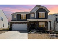 Charming two-story home featuring a mix of stone and siding, attached two-car garage and a welcoming front porch at 2039 Morning Gold Dr, Maiden, NC 28650