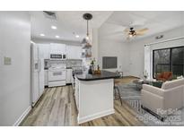 Bright, open living space featuring a modern kitchen with white appliances and an adjacent living room with a ceiling fan at 211 Heritage Blvd # 301, Fort Mill, SC 29715